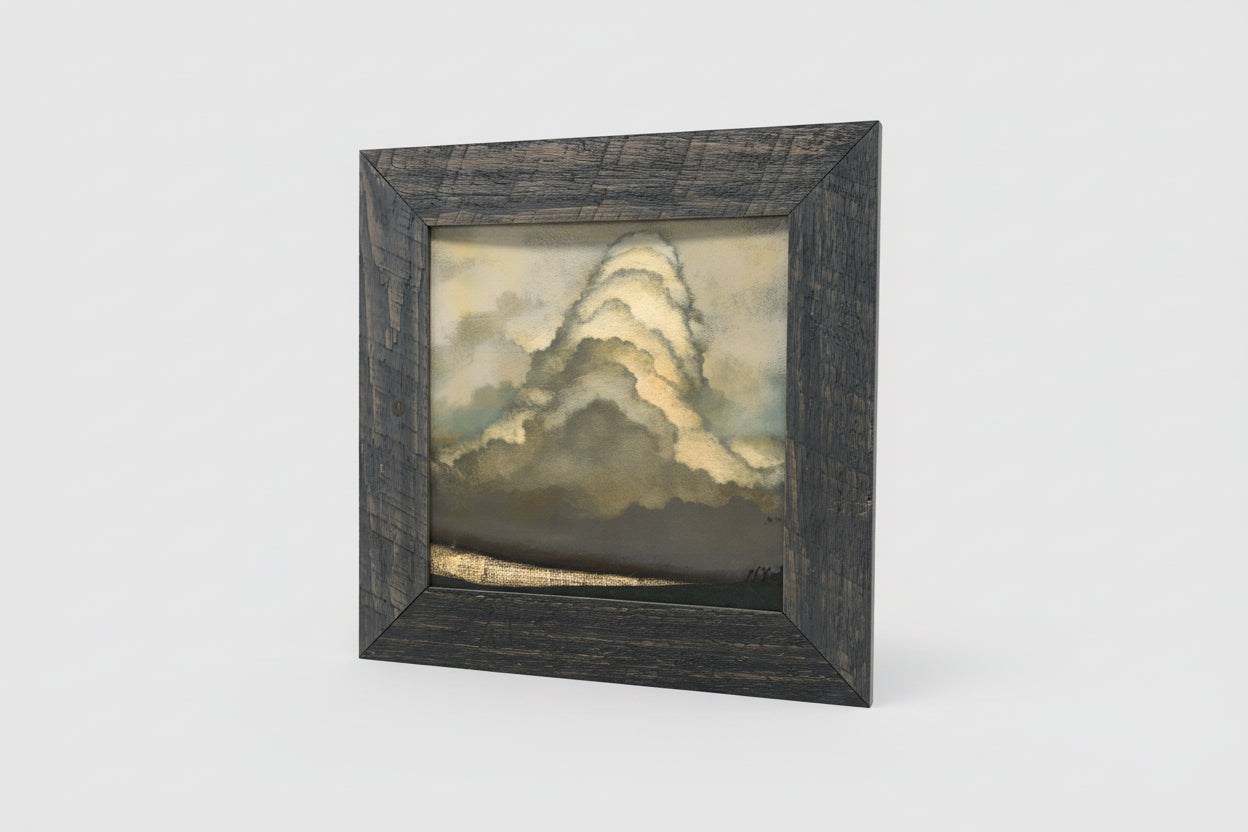 An oil painting depicting a stormy sky, framed in a rustic wooden frame, displayed on a wooden surface.