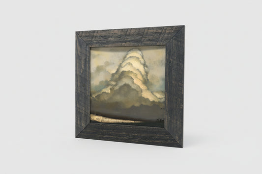 An oil painting depicting a stormy sky, framed in a rustic wooden frame, displayed on a wooden surface.
