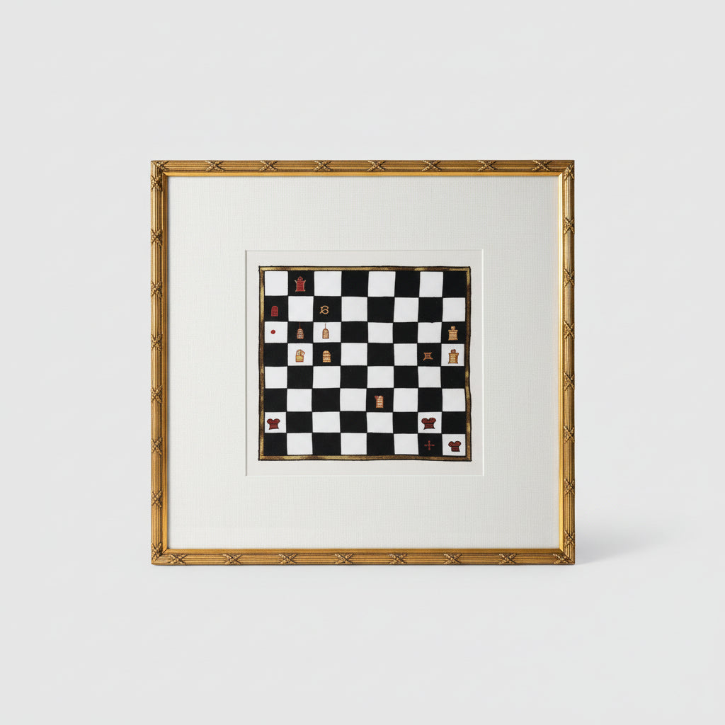 A framed decorative chess board with ornate gold frame, displayed on a wooden surface with a ball-shaped decorative item to the side.