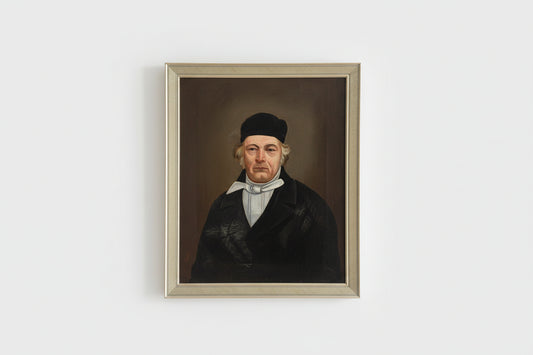 An antique oil painting of a man in black attire, displayed in a gold frame, placed on a wooden surface with a decorative item to the left.