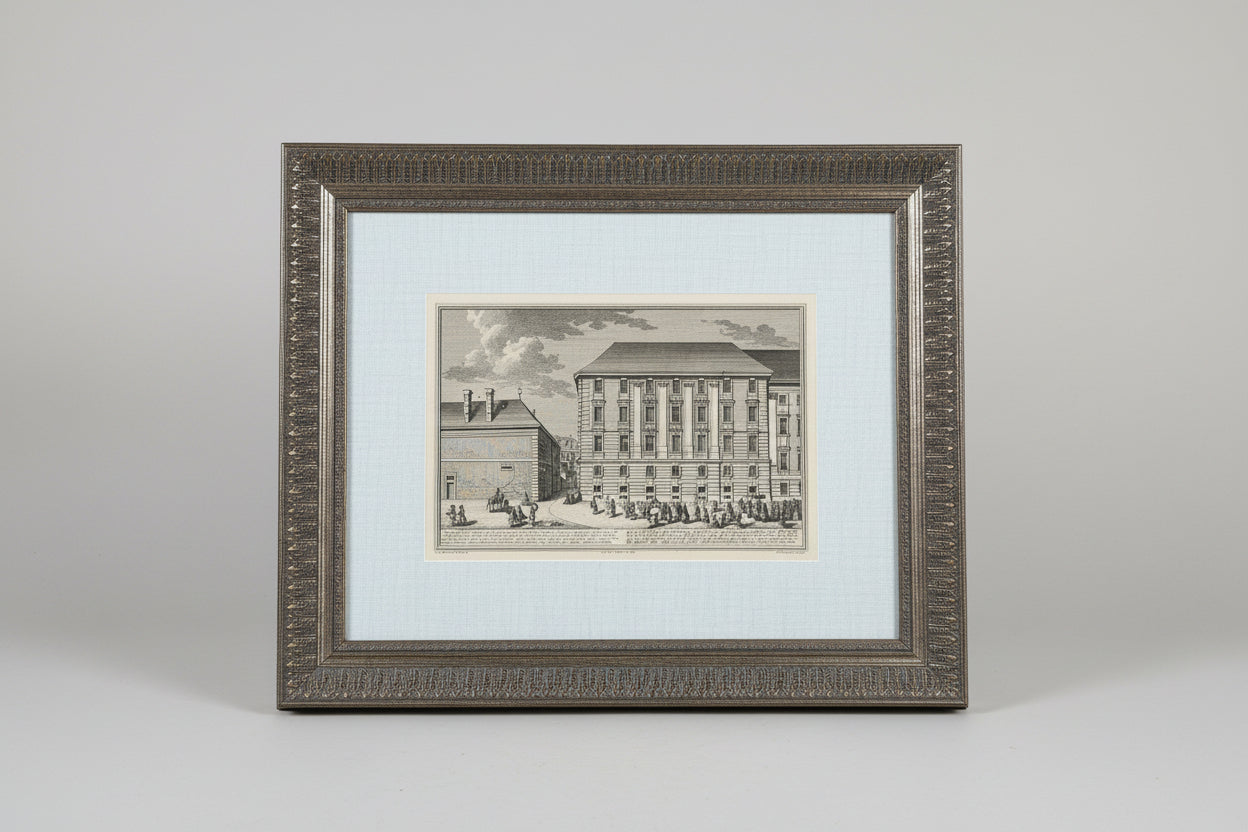 A black and white architectural etching in a custom antique frame, depicting a building, displayed on a wooden surface.