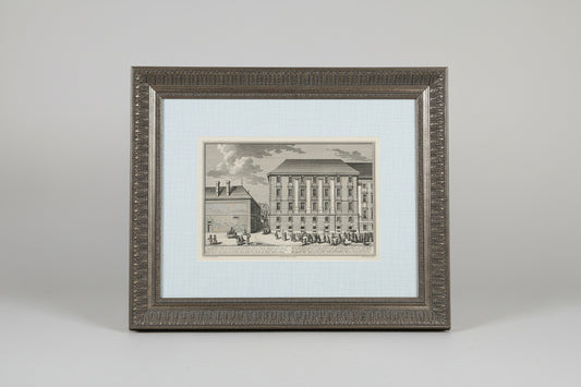 A black and white architectural etching in a custom antique frame, depicting a building, displayed on a wooden surface.