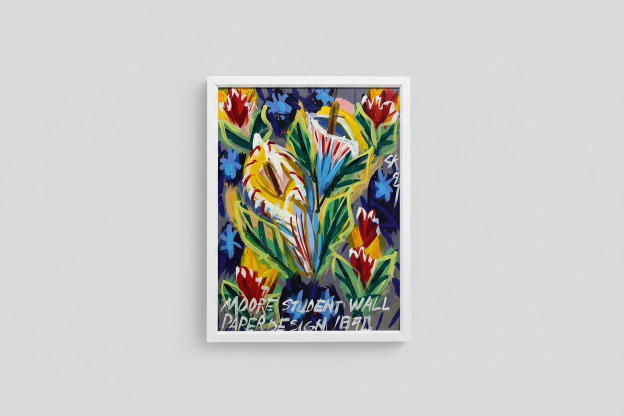 A colorful floral oil on board painting, framed, displayed on a wooden table with a sculpture beside it, illuminated by natural light.
