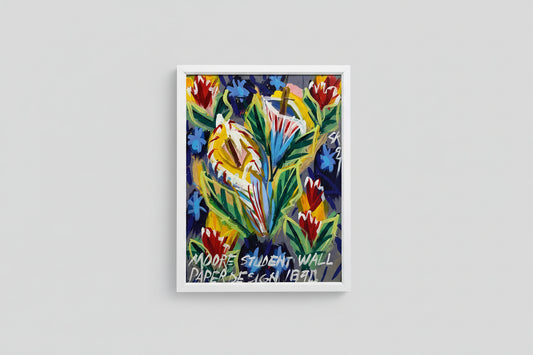 A colorful floral oil on board painting, framed, displayed on a wooden table with a sculpture beside it, illuminated by natural light.