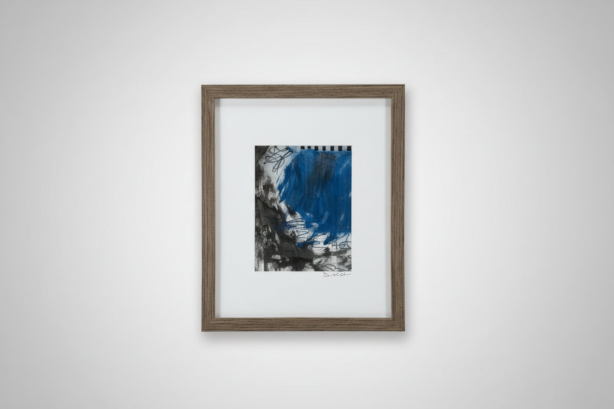 A framed mixed media artwork featuring a blue and gray abstract pattern, displayed on a wooden surface with a custom-made frame.