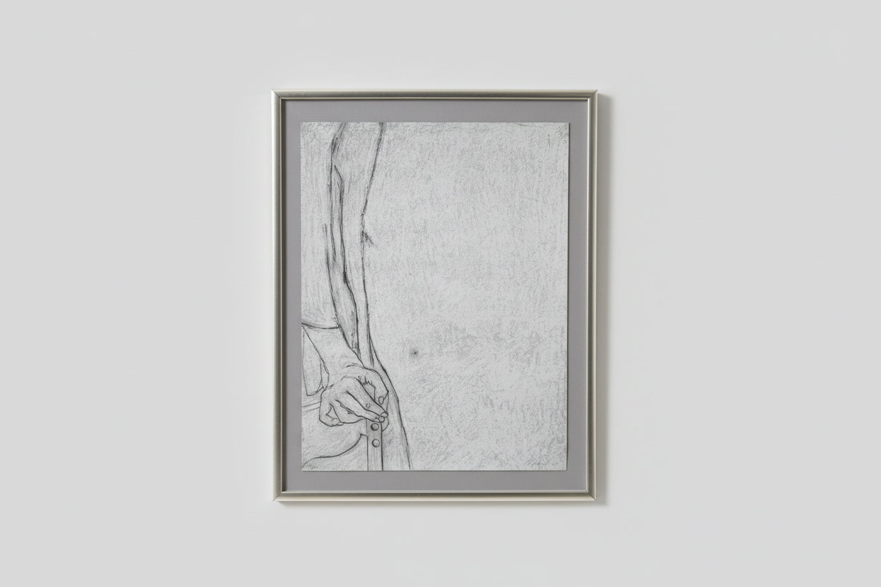 A framed lithograph drawing, depicting a figure with a contemplative expression, displayed on a wall above a wooden table with two black sculptures beside it.