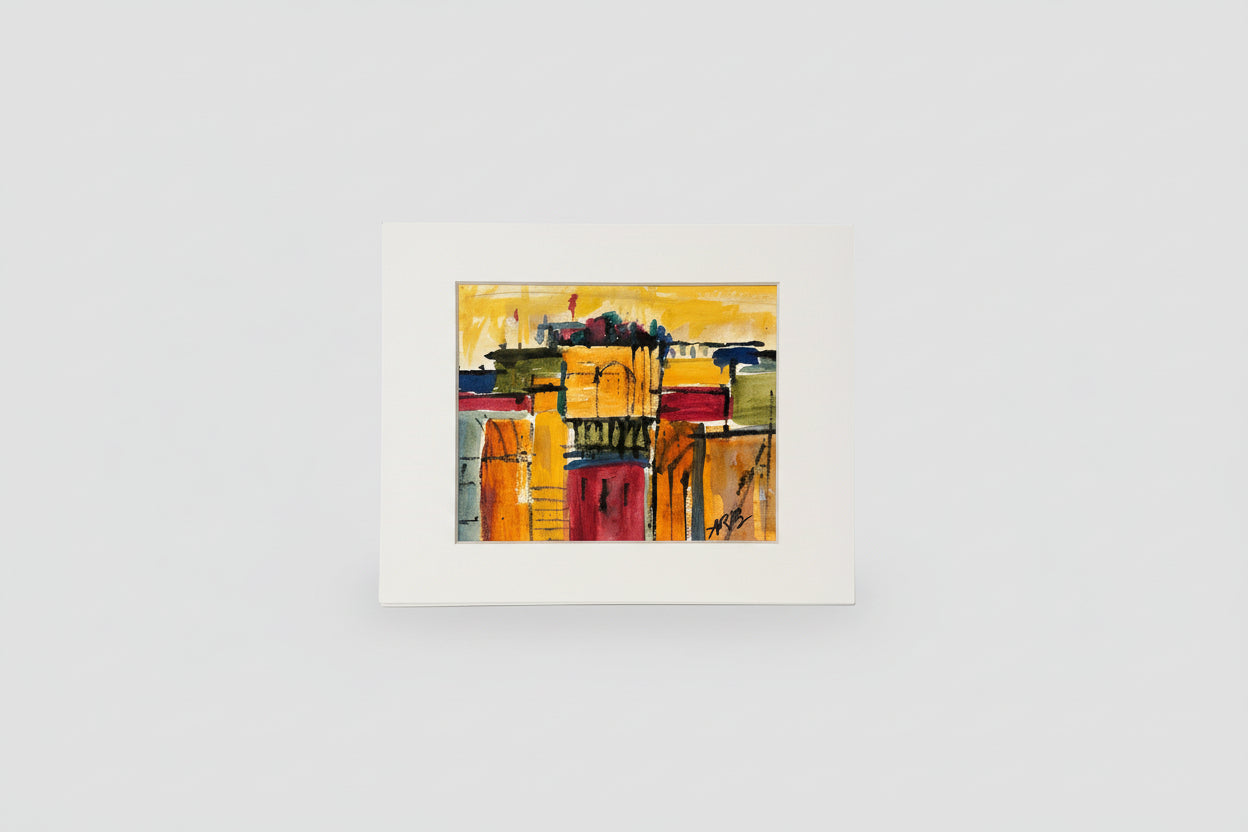 A framed mixed media artwork featuring vibrant colors, displayed on a flat surface with a blurred background.