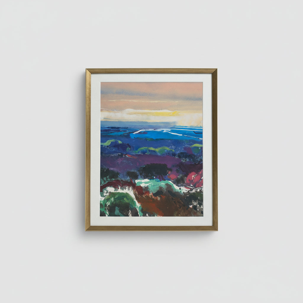 A framed mono print of a vibrant landscape view hanging on a wall, with a white frame and visible brushstrokes.