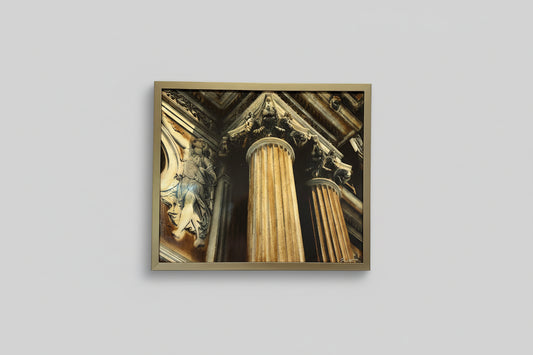 A framed artwork featuring a photo collage of architectural elements, presented in a gold frame, displayed on a wall.