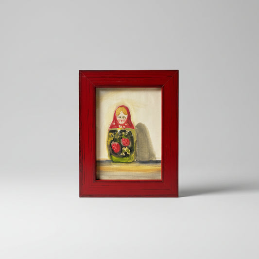 A framed oil painting on board depicting a colorful character, displayed on a dark surface against a neutral wall.