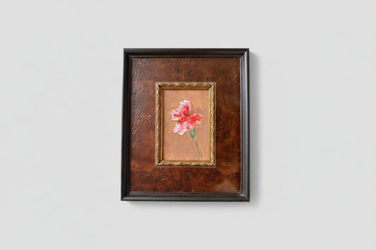 An oil painting of pink flowers on a board, framed in a burl wood frame, displayed on a wall.