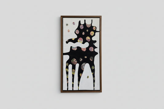 An artwork with a fantastical creature in a gold frame, displayed on a wall in a bright room with a piece of greenery on a table.