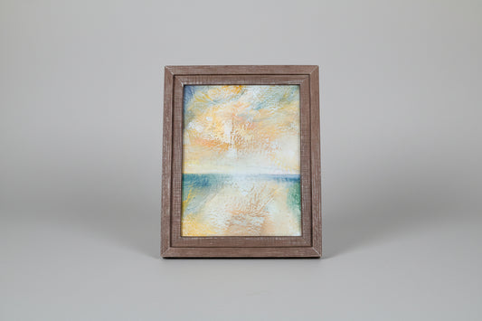 Framed abstract painting on a wooden surface with a blurred background